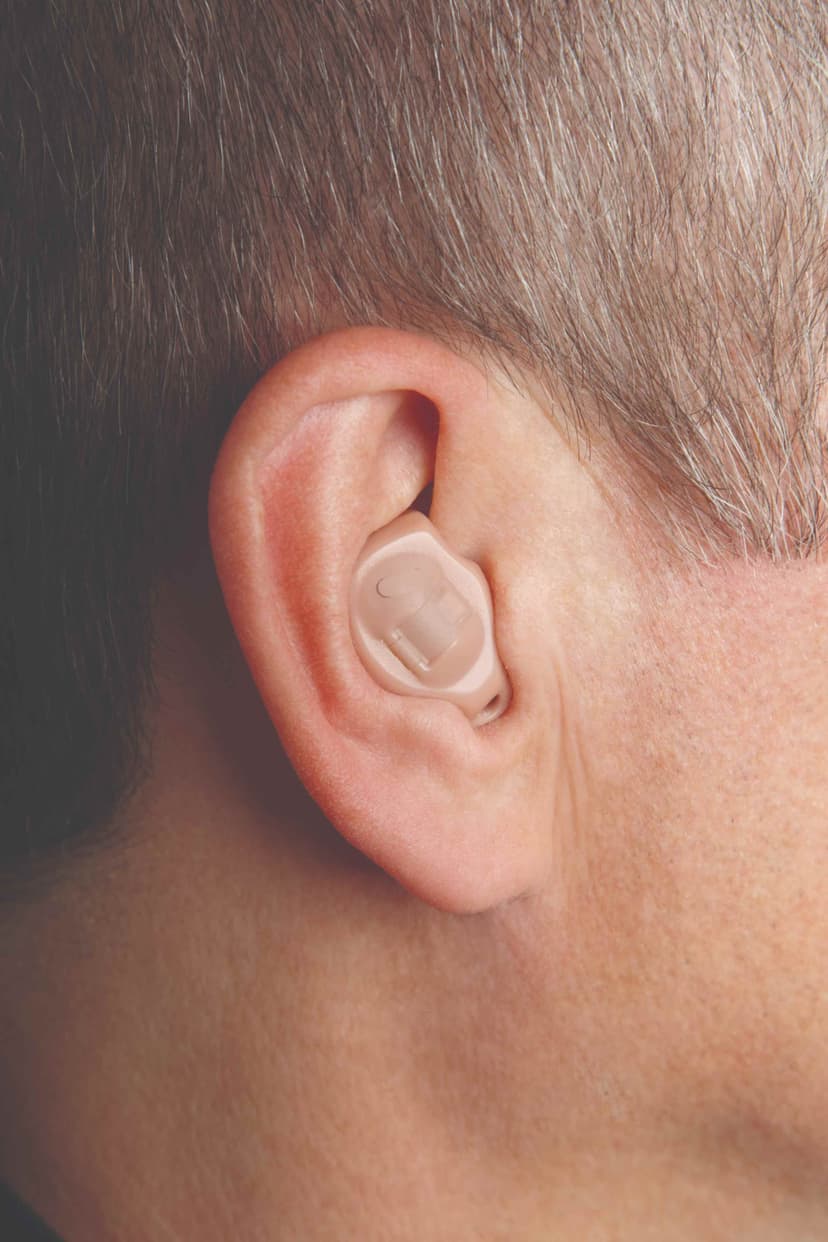 Close-up of a person's ear with an ITE hearing aid filling the concha bowl