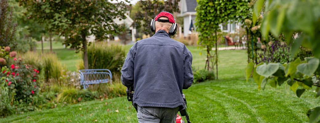Man wearing protective earmuffs while mowing a lawn